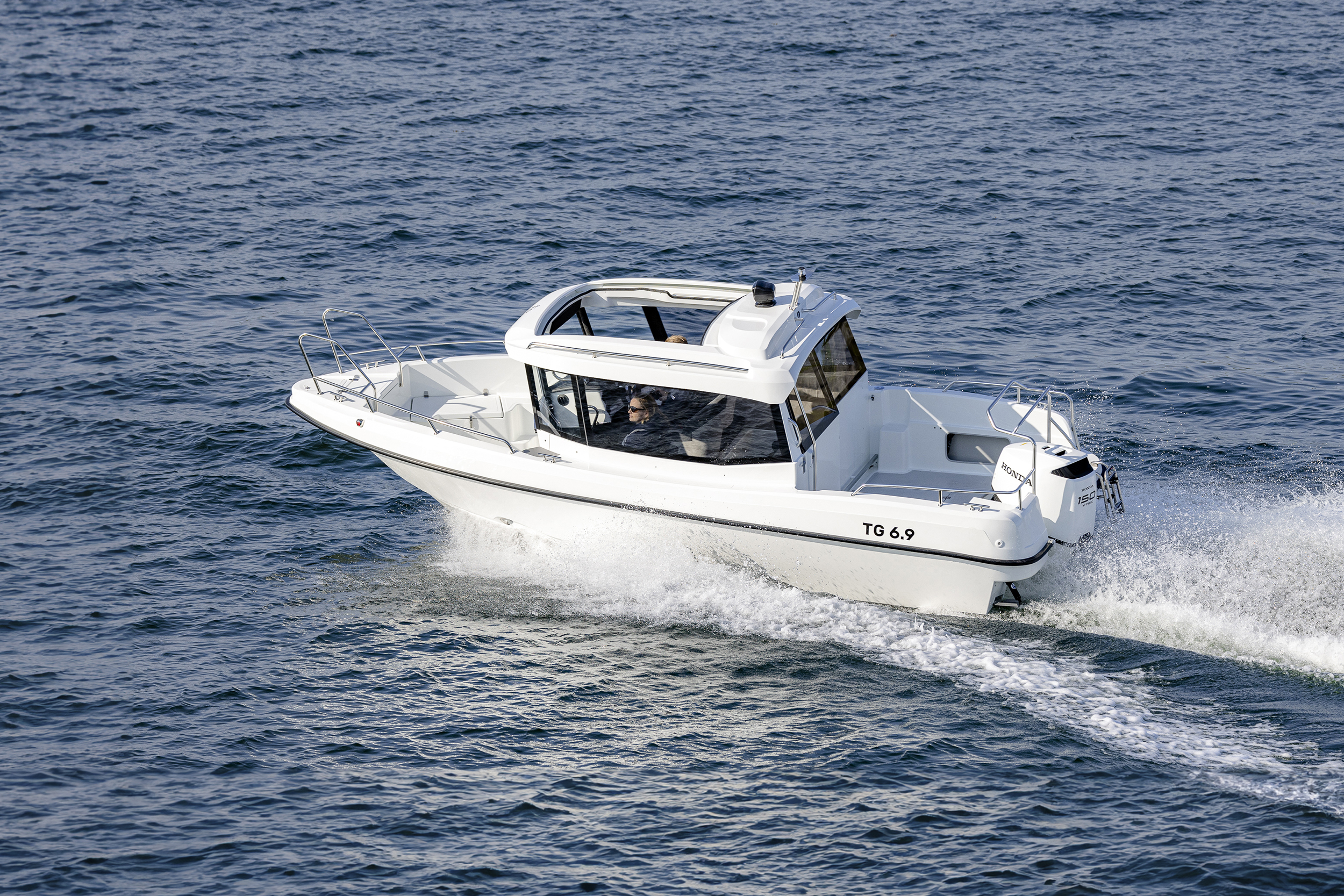 TG 6.9 kabinbåt kör i hög fart på öppet hav med takluckan öppen.