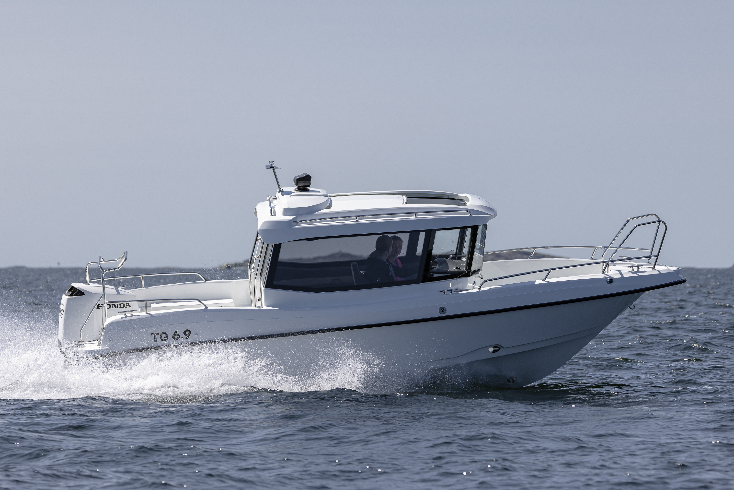 TG 6.9 -kabinbåt kör i hög fart på öppet hav i yttre skärgården. Strålande sol.