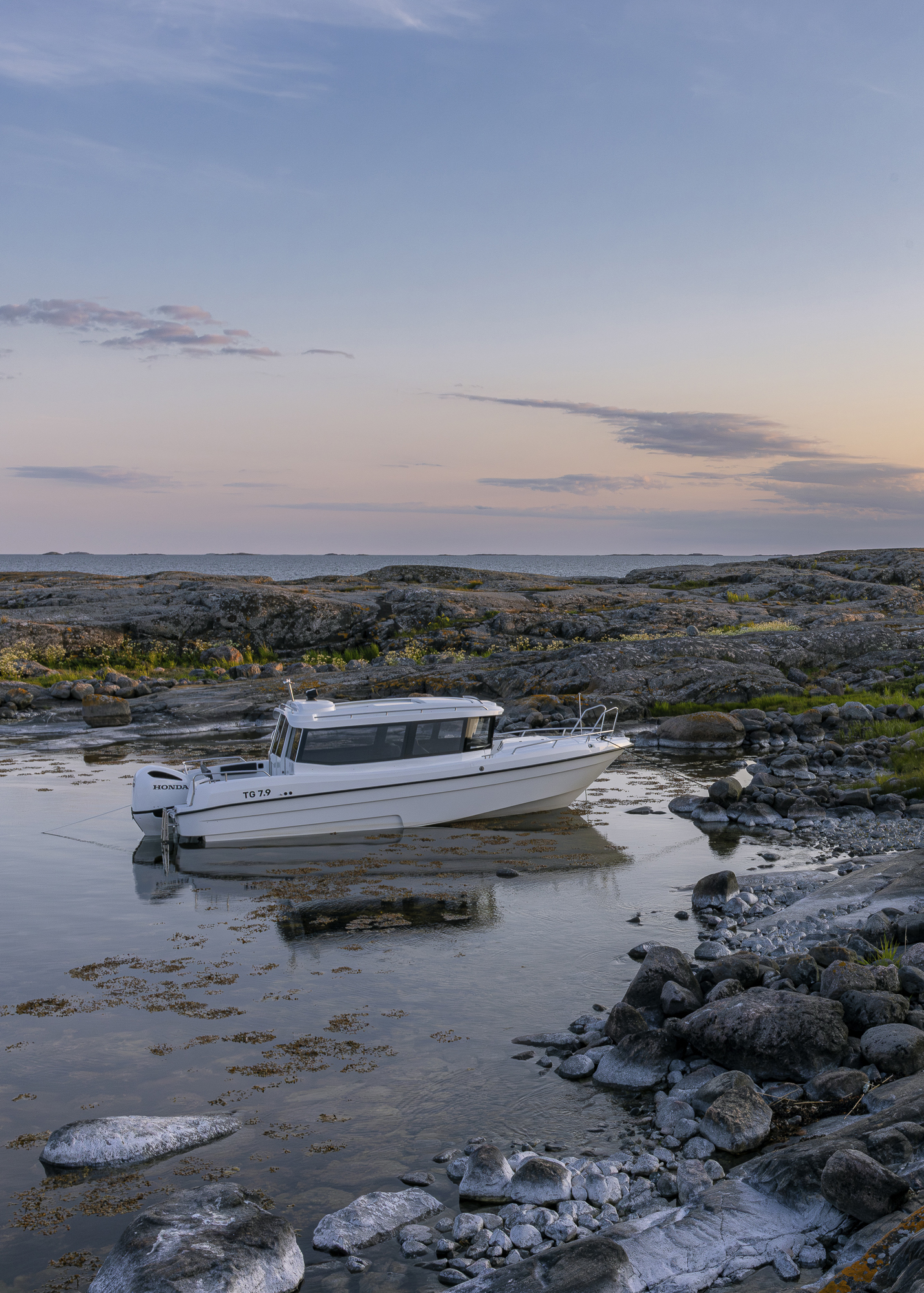 TG 7.9 cabin boat anchored in beaufitul, serene natural harbor in the outer Finnish archipelago at sunset.