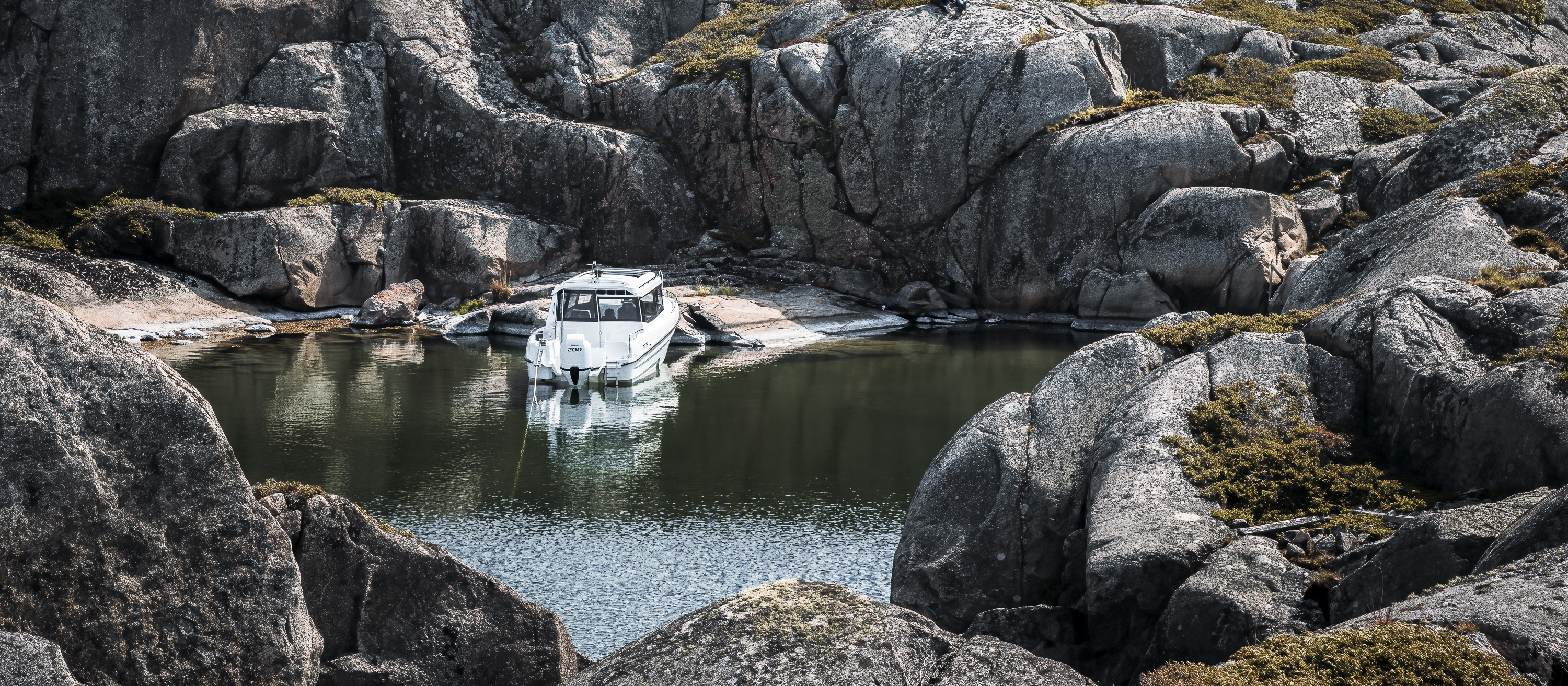 TG 7.9 hyttbåt står för ankare i yttre skärgården, omgiven av ståtliga klippor.